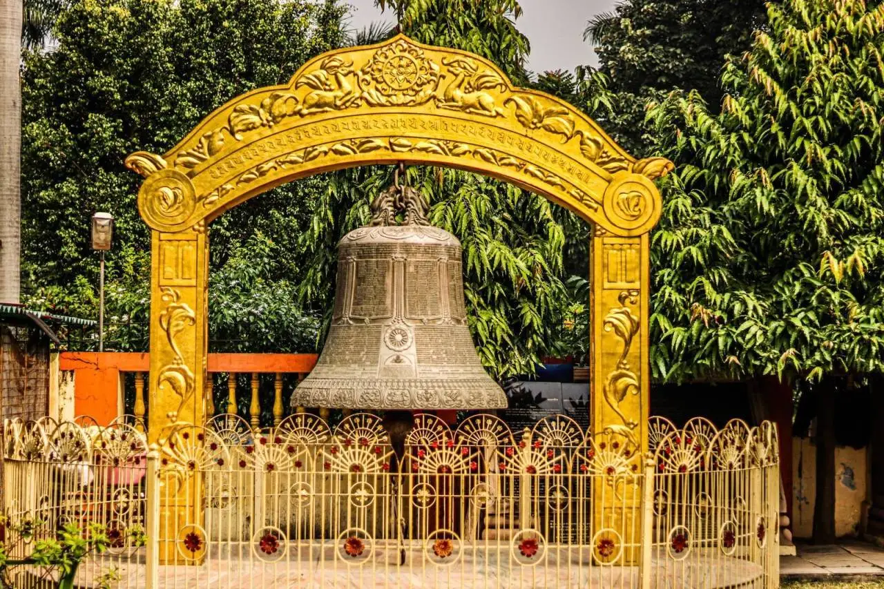 Giant engraved bell at Mulagandhakuti Vihara with ornate details in Sarnath, India.
