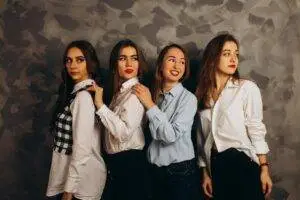 Four women in fashionable casual attire pose elegantly in a studio shoot.