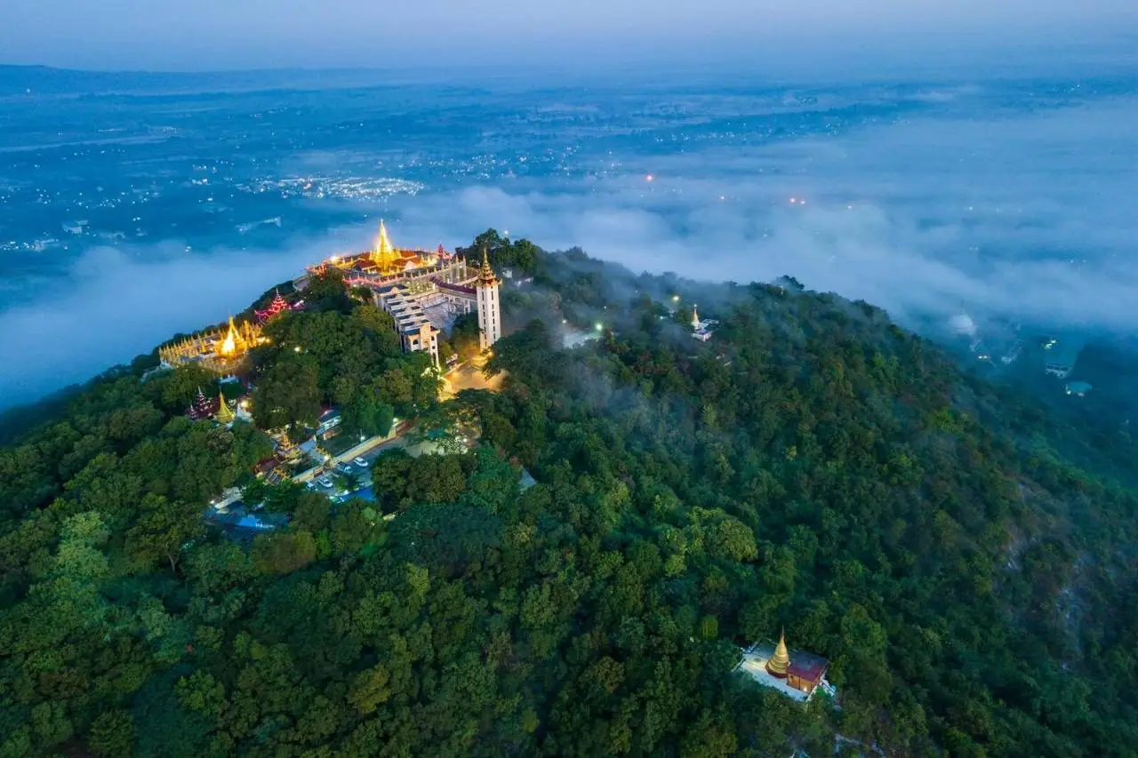 Stunning aerial view of Mount Popa Monastery enveloped in mist, Myanmar at dawn.