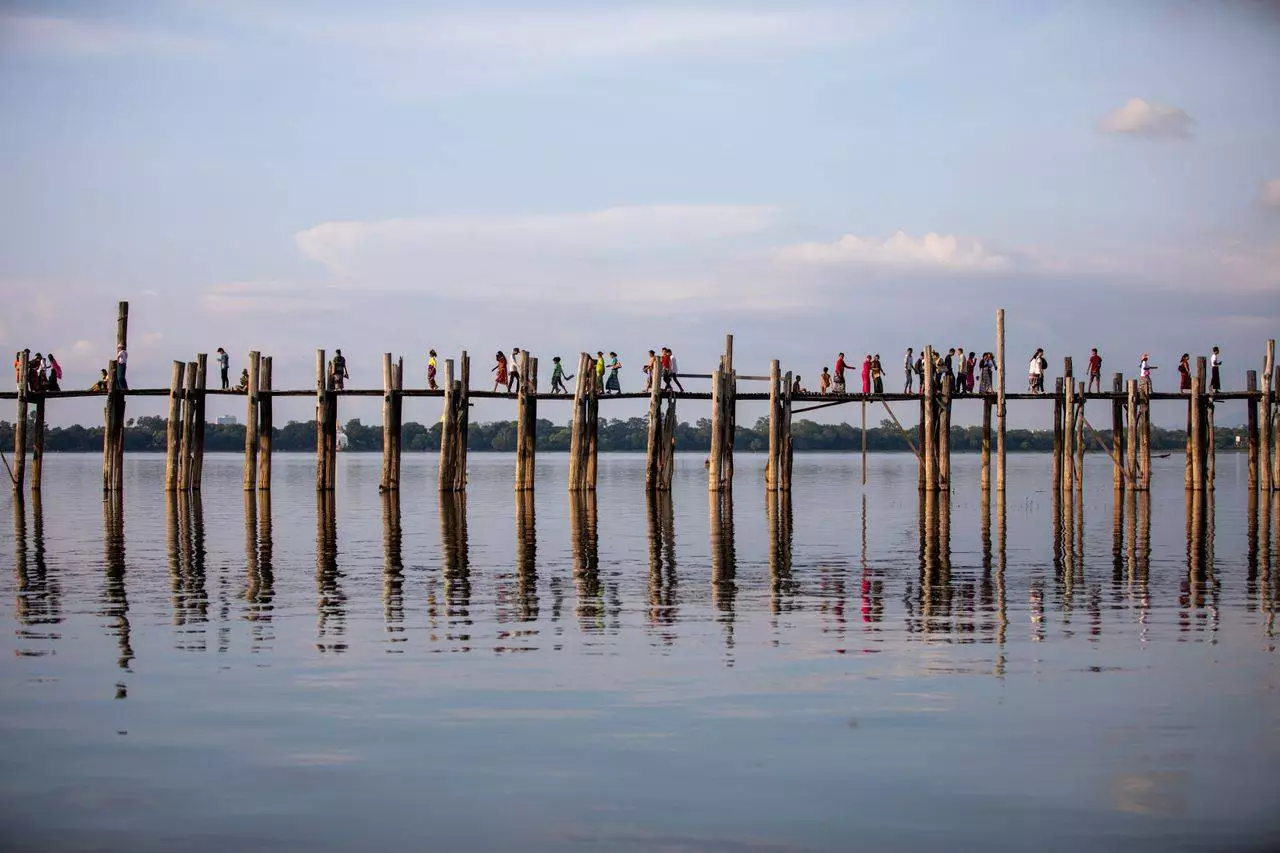 Visitors walking along U Bein Bridge over Taungthaman Lake representing Mandalay's most iconic sunset destination in 2026